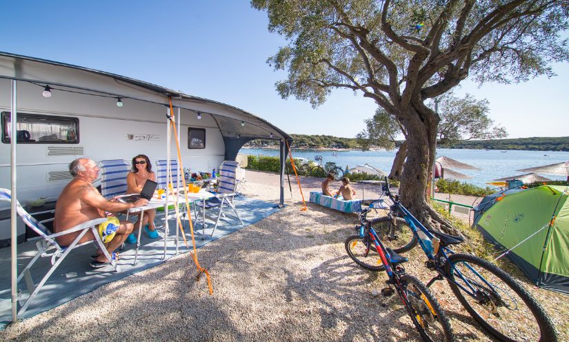 gezin naast caravan naturistencamping aan zee